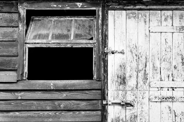 一扇打开的窗户旁边的木制马厩门的黑白视图。图片下载