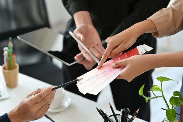 近距离观察设计师或创意工作者在办公室一起工作，并指向一个调色板，为艺术、设计、技术和商业概念。图片下载