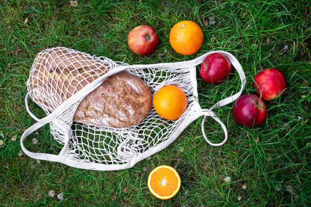 水果和新鲜面包装在草丛里的绳袋里。图片下载