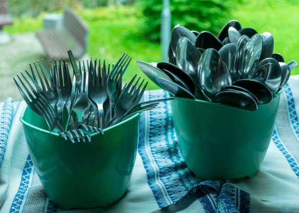 学校厨房食堂，绿色塑料容器中的金属勺子和刀具，食堂设备，学校厨房图片下载