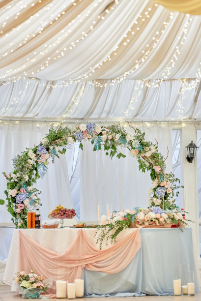 婚礼主席团在餐厅，复印空间。新婚夫妇的宴席上摆放着鲜花、绿叶、蜡烛和粉红色的桌布。郁郁葱葱的插花艺术。豪华婚礼装饰图片下载