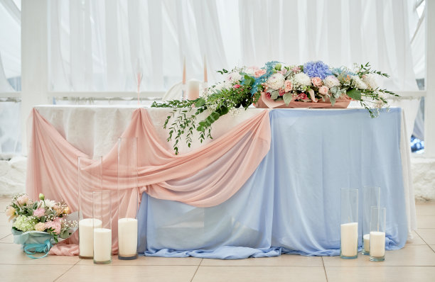 婚礼主席团在餐厅，复印空间。新婚夫妇的宴席上摆放着鲜花、绿叶、蜡烛和粉红色的桌布。郁郁葱葱的插花艺术。豪华婚礼装饰图片下载