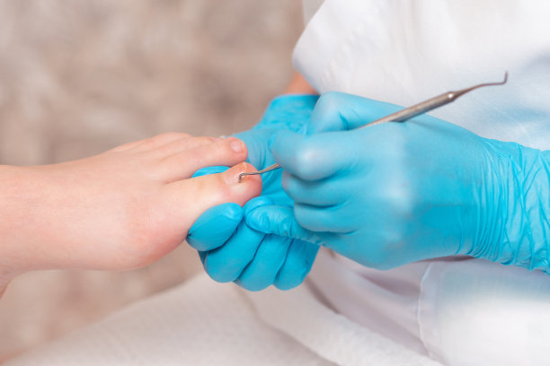 足疗师为客户的脚做足疗，用双面刮刀清洁指甲。关闭了。足疗沙龙理念专业护理图片下载