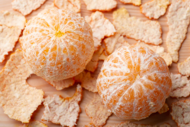 两个剥了皮的橘子放在木桌上图片下载