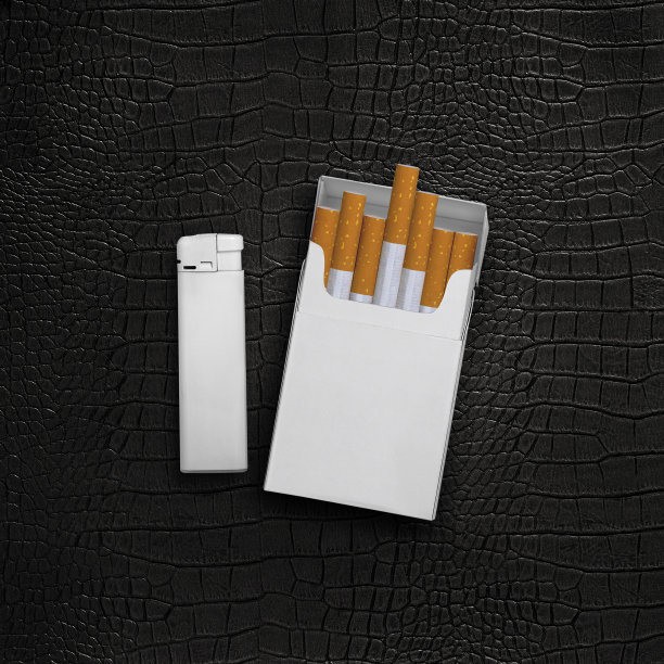 黑色皮革背景上的烟盒和打火机图片下载