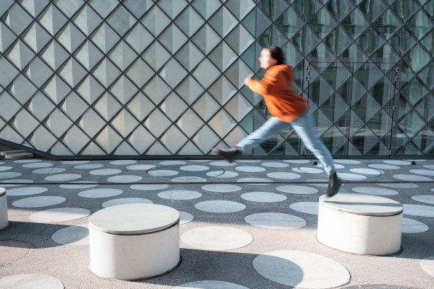 运动模糊的女人从长凳跳到长凳上白色斑点的城镇广场图片下载