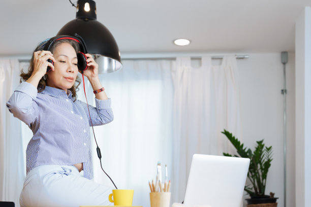 放松时间，一位老妇人的肖像听着音乐愉快地放松在电脑会话之间图片下载