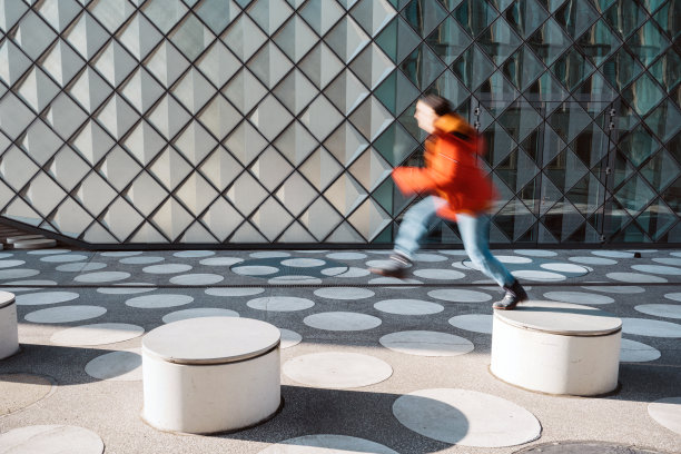 运动模糊的女人从长凳跳到长凳上白色斑点的城镇广场图片下载