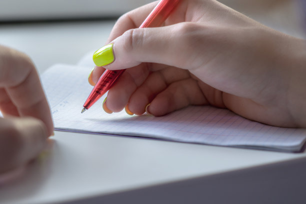 女人手里拿着红笔，在笔记本上写字图片下载