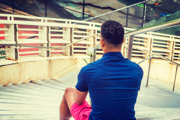 纽约，年轻人手捧白玫瑰，坐在室外的楼梯上图片下载