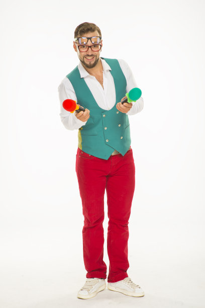 拿麦克风的人在笑。一个兴高采烈的家伙，手里拿着两个麦克风，脸上戴着两副眼镜，穿着红色裤子和背心，在一个孤立的白色背景上滑稽地摆着姿势图片下载