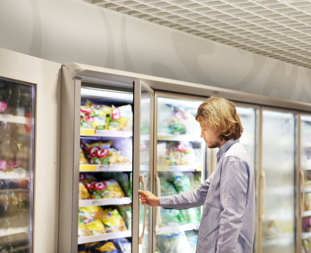 男人从超市冰柜选择冷冻食品并阅读产品信息图片下载