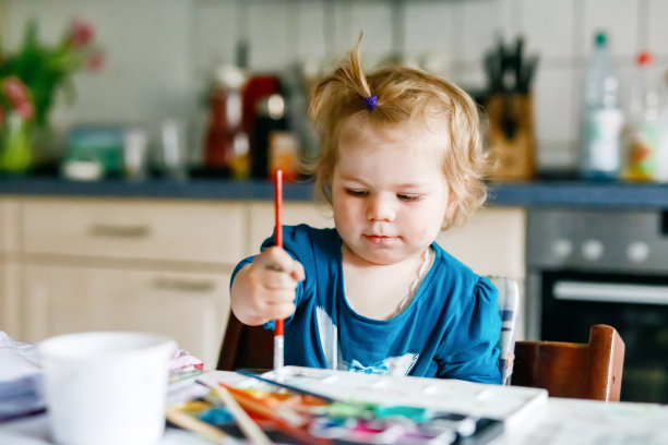可爱快乐的小女孩用水彩画在纸上。宝宝学习不同的幼儿技能，为幼儿提供创造性的休闲活动。图片下载