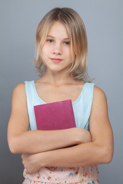 小女孩拿着灰色背景的书图片下载