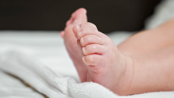 光着脚的新生女婴躺在白色的床单上做着动作图片下载