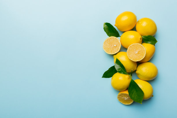 许多新鲜成熟的柠檬与绿叶彩色背景，俯视图，文字空间图片下载