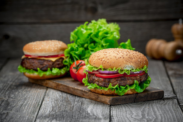 旧木桌上放着两个美味的自制牛肉汉堡。脂肪不健康食品特写。图片下载