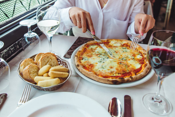 一名女子在餐厅吃披萨喝红酒的剪报照片图片下载