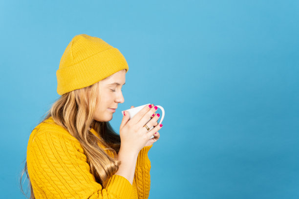 侧视图的金发年轻女子闻一杯咖啡图片下载