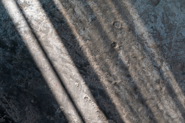 阴影和阳光斜射在混凝土地板上。肮脏、尘土飞扬的地板上抽象化的影子。为不同的设计问题提供多任务背景。图片下载