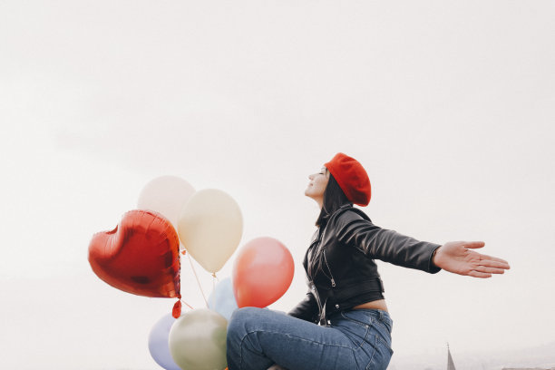 女人举着五颜六色的气球冲向天空图片下载