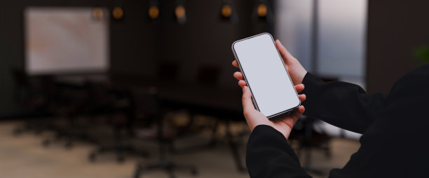 一个女商人拿着一个手机模型在模糊的现代会议室的背景。图片下载