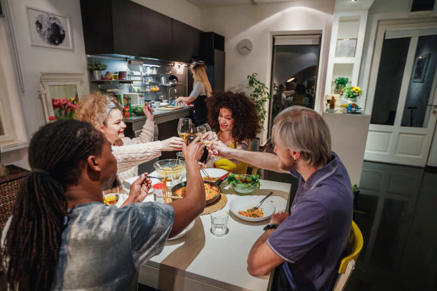 一群快乐的年轻人坐在家里的餐桌旁举杯祝酒图片下载