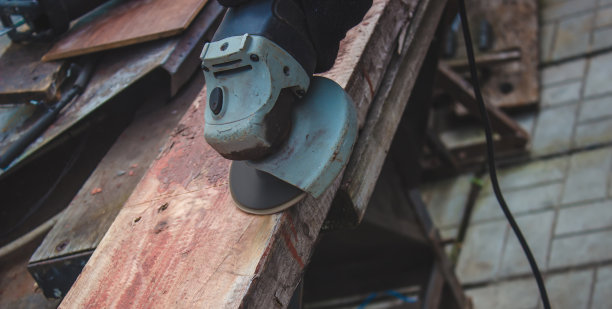 一个人正在磨一块木板。清除木板上的旧油漆。木工工作。图片下载