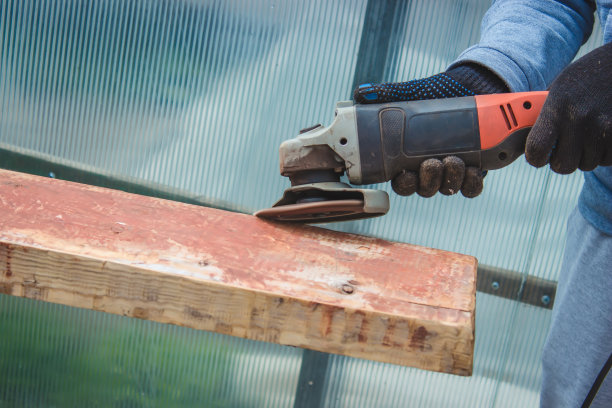 一个人正在磨一块木板。清除木板上的旧油漆。木工工作。图片下载