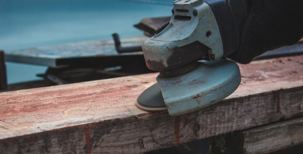 一个人正在磨一块木板。清除木板上的旧油漆。木工工作。图片下载