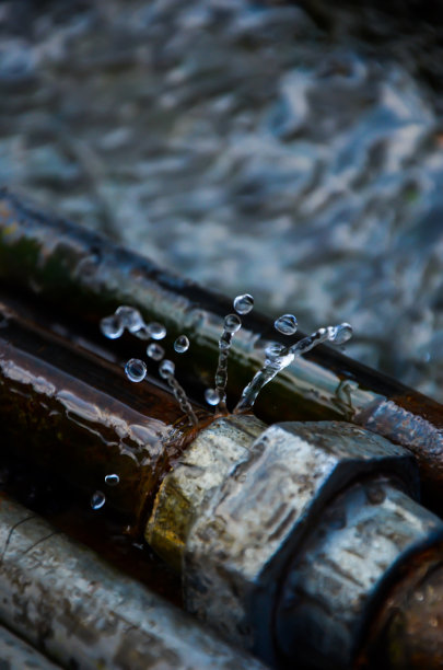 街上的连接管漏水。钢管接头水的浪费。水从阀门接头上飞溅和滴水。图片下载