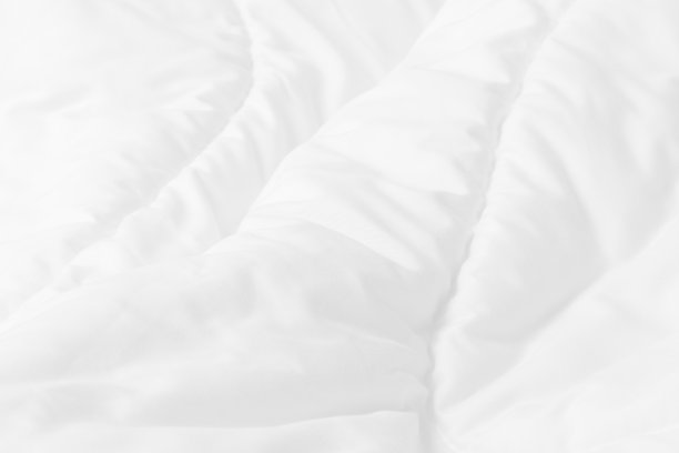 早晨醒来后，卧室里白色床单和皱乱的毯子的特写俯视图。图片下载