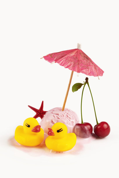 融化的樱桃冰淇淋配上纸伞和橡胶小鸭子图片下载