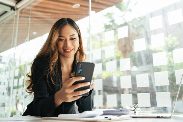亚洲商业女性在办公室穿着正式的西装愉快地使用智能手机和工作图片下载