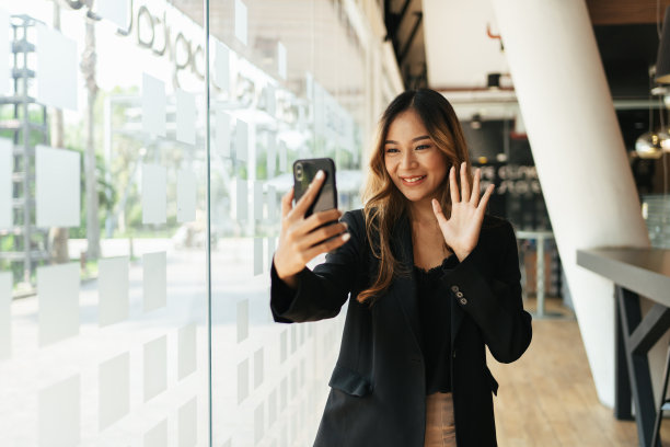 快乐的女商人微笑着在办公室用手机打视频电话。图片下载