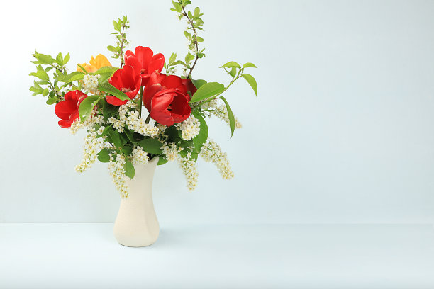 室内装饰元素的家，美丽的春天树枝鸟樱桃和郁金香在一个浅的背景上的花瓶，抽象的插花，静物与文字的地方，图片下载