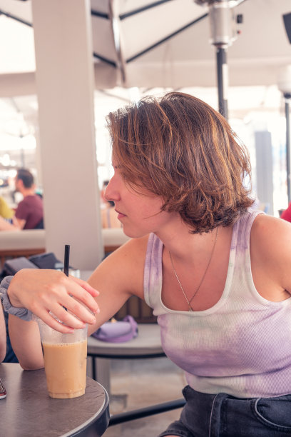 一位女士在咖啡馆里专心地喝着冰咖啡图片下载