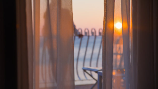 站在酒店阳台上欣赏日落美景的女子图片下载