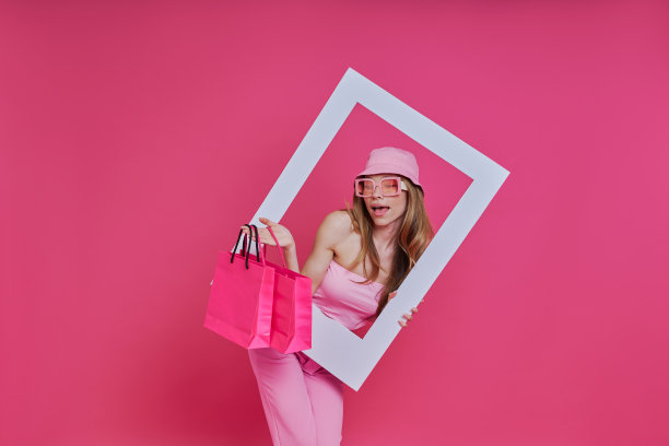 快乐的女人看着相框，拎着购物袋图片下载