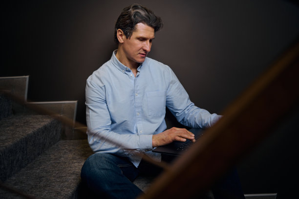 自信成熟经验丰富的企业家、商人坐在家里室内的楼梯上用笔记本电脑工作。远程专业，在线业务和项目概念。图片下载