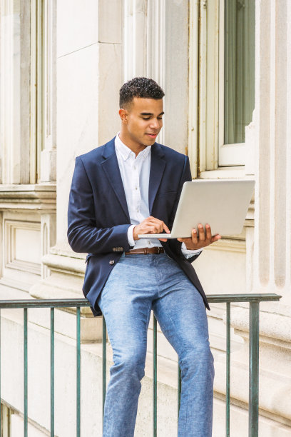 一个年轻人坐在纽约的办公楼外，用笔记本电脑工作图片下载