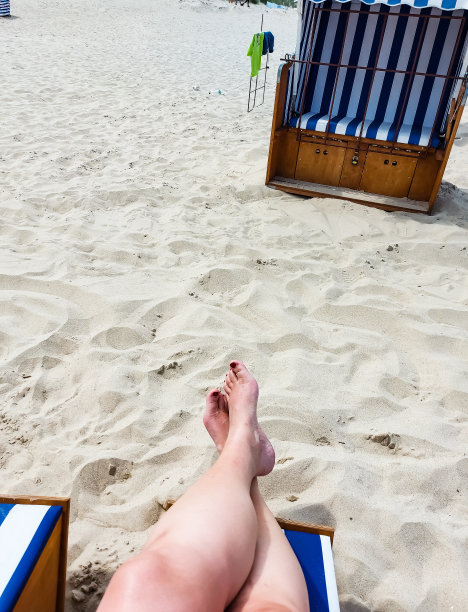 一个人坐在沙滩椅上，举起他们的脚图片下载