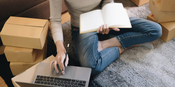 创办小企业中小企业业主女企业家在收货箱上写上地址，核对网上订单，准备装箱，卖给客户，中小企业网上经营思路。图片下载