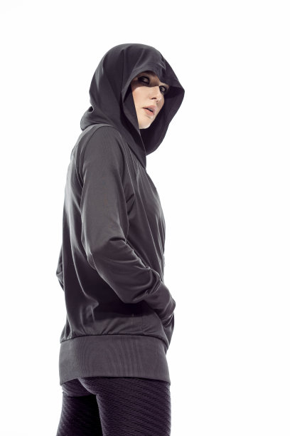 迷人的运动白人女运动员的肖像在黑色帽衫，而穿着健身装备和向后看对白色背景。图片下载