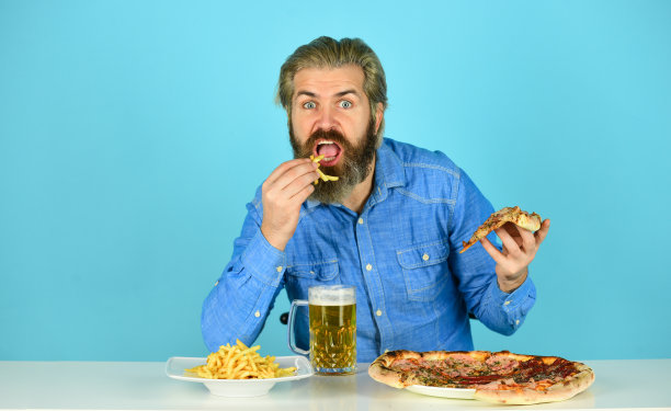 披萨店的餐厅。披萨派对的概念。把幸福送进嘴里。啤酒和食物。快乐的男人，留着胡子的嬉皮士吃披萨。晚餐在酒吧。饥饿的人要吃披萨和喝啤酒图片下载
