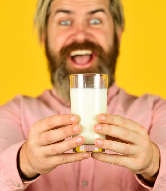 喝鸡尾酒的蛋白质。健康的习惯。杏仁奶富含多种健康营养物质。牛奶有益健康。乳糖免费。大胡子男人拿着一杯牛奶。钙的来源。纯牛奶的概念图片下载
