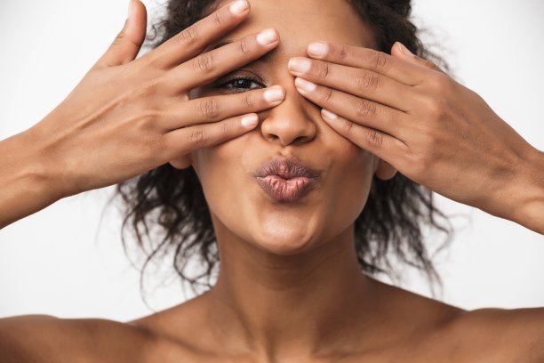 年轻的非洲妇女摆孤立在白色的墙壁背景覆盖眼睛与手。图片下载