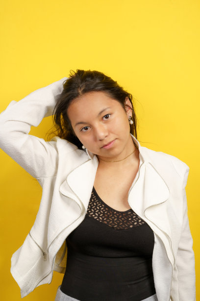 欢快的年轻拉丁女孩的肖像，穿着青春潮流的衣服，举起手臂，看着镜头图片下载