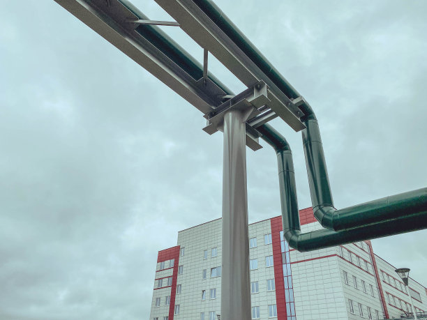 建筑工地的天然气管道。装有天然气的狭窄管道通过管道将资源运送到交货点。房屋背景上的绿色天然气管道图片下载