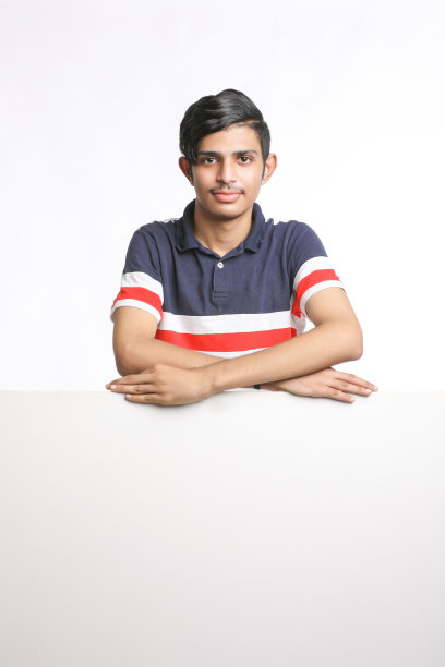 年轻的印度男子在白色背景上展示空白的歌唱板。图片下载